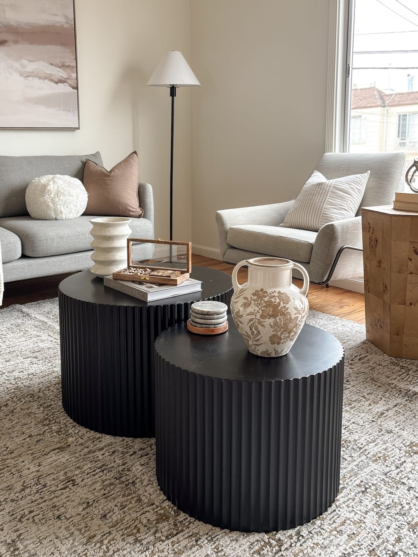 Staged living room with black fluted nesting tables and soft grey seating