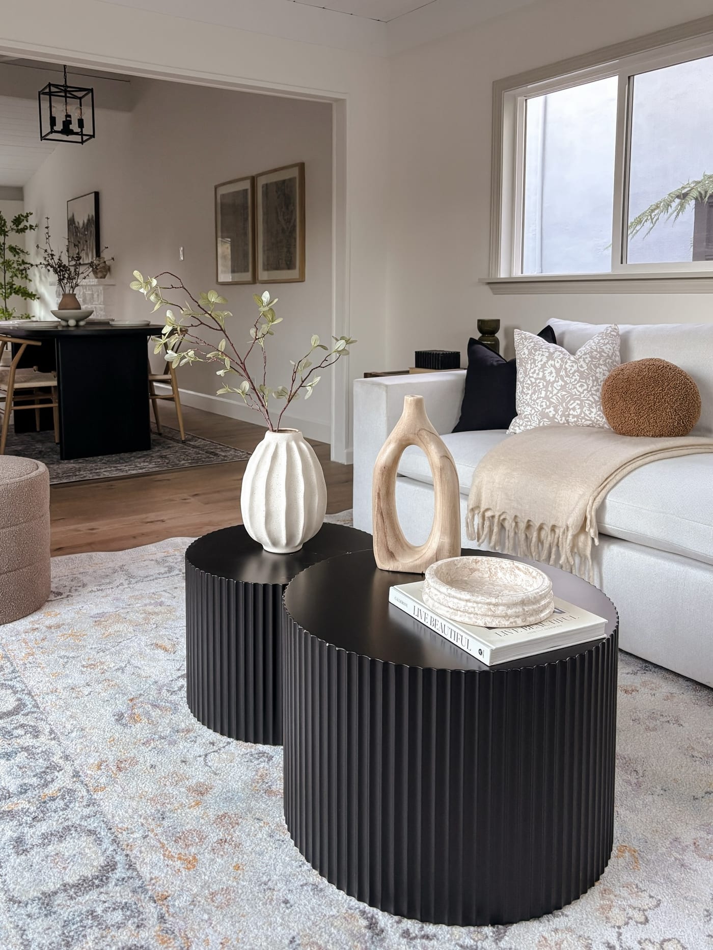 Staged open living and dining with black fluted nesting tables and a white sectional