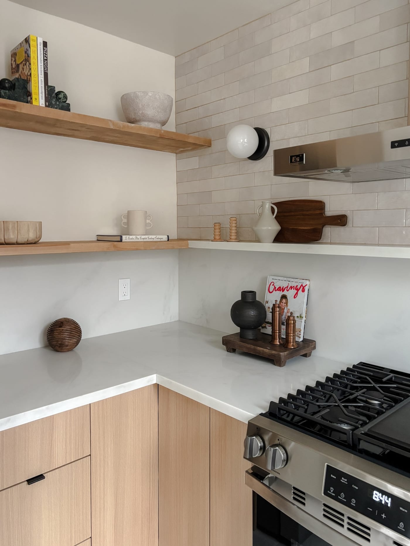 Styled kitchen corner with floating oak shelves and stacked subway tile