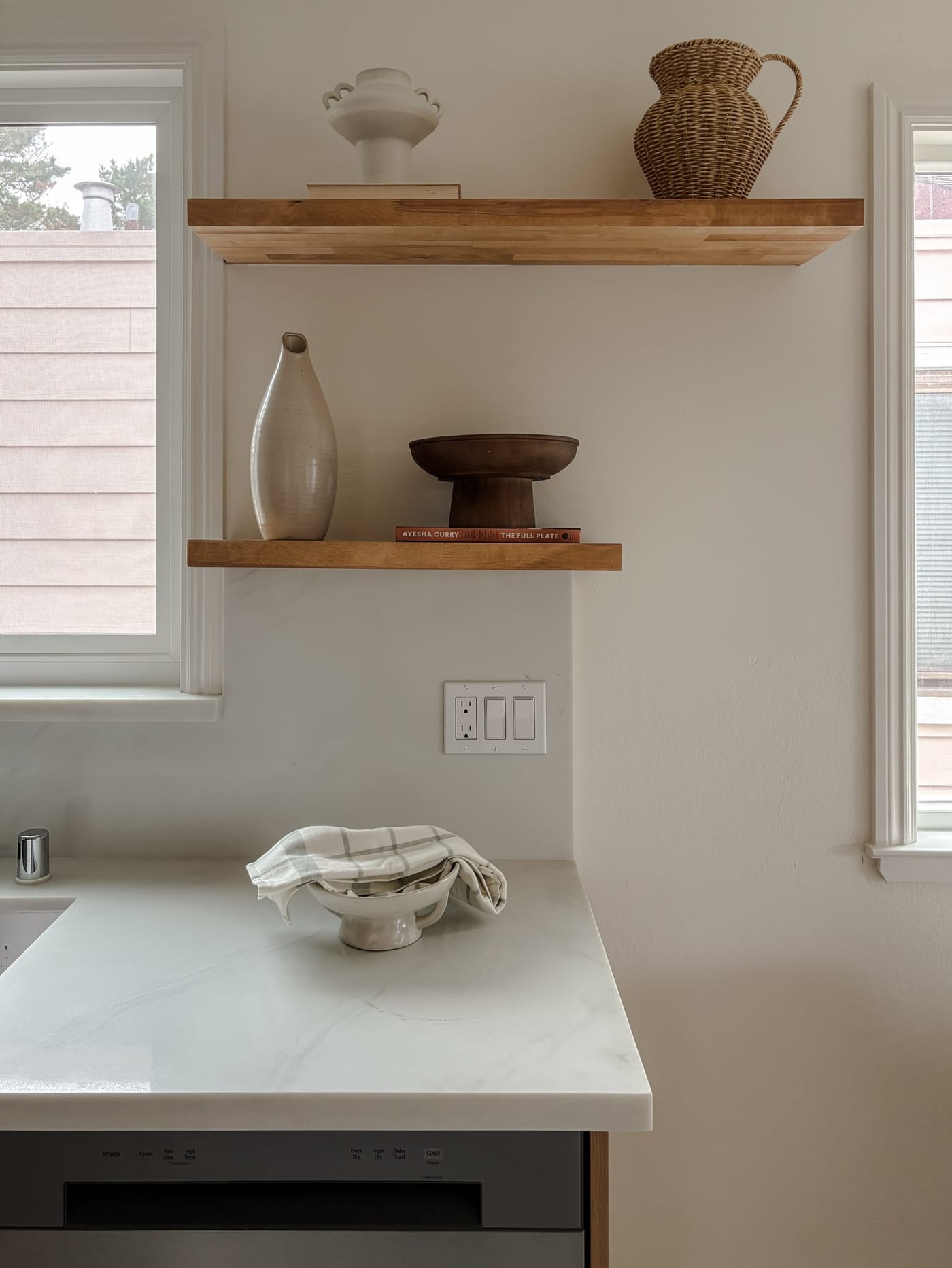 Styled kitchen vignette with floating oak shelves and a marble waterfall counter