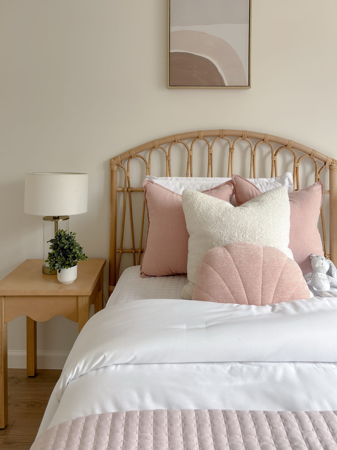 Staged bedroom with a rattan headboard and soft pink accents