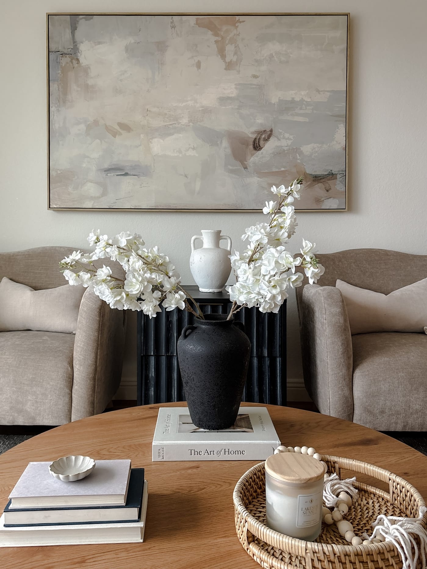 Staged living room vignette with a black urn of white blossoms and a fluted console