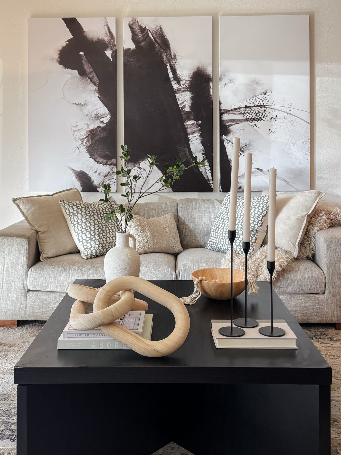 Staged living room with a black-and-white triptych and a black coffee table