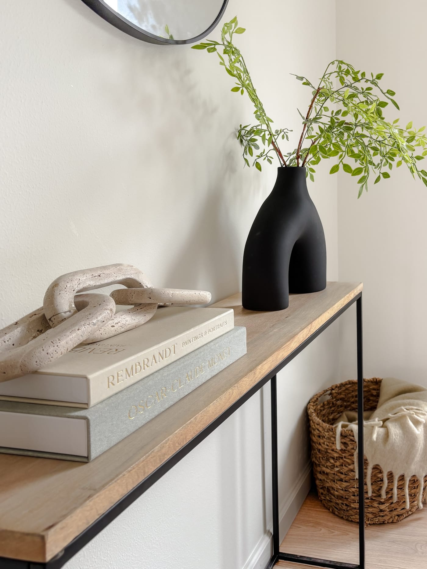 Styled entryway with a wood-and-metal console, round mirror, and fresh greenery