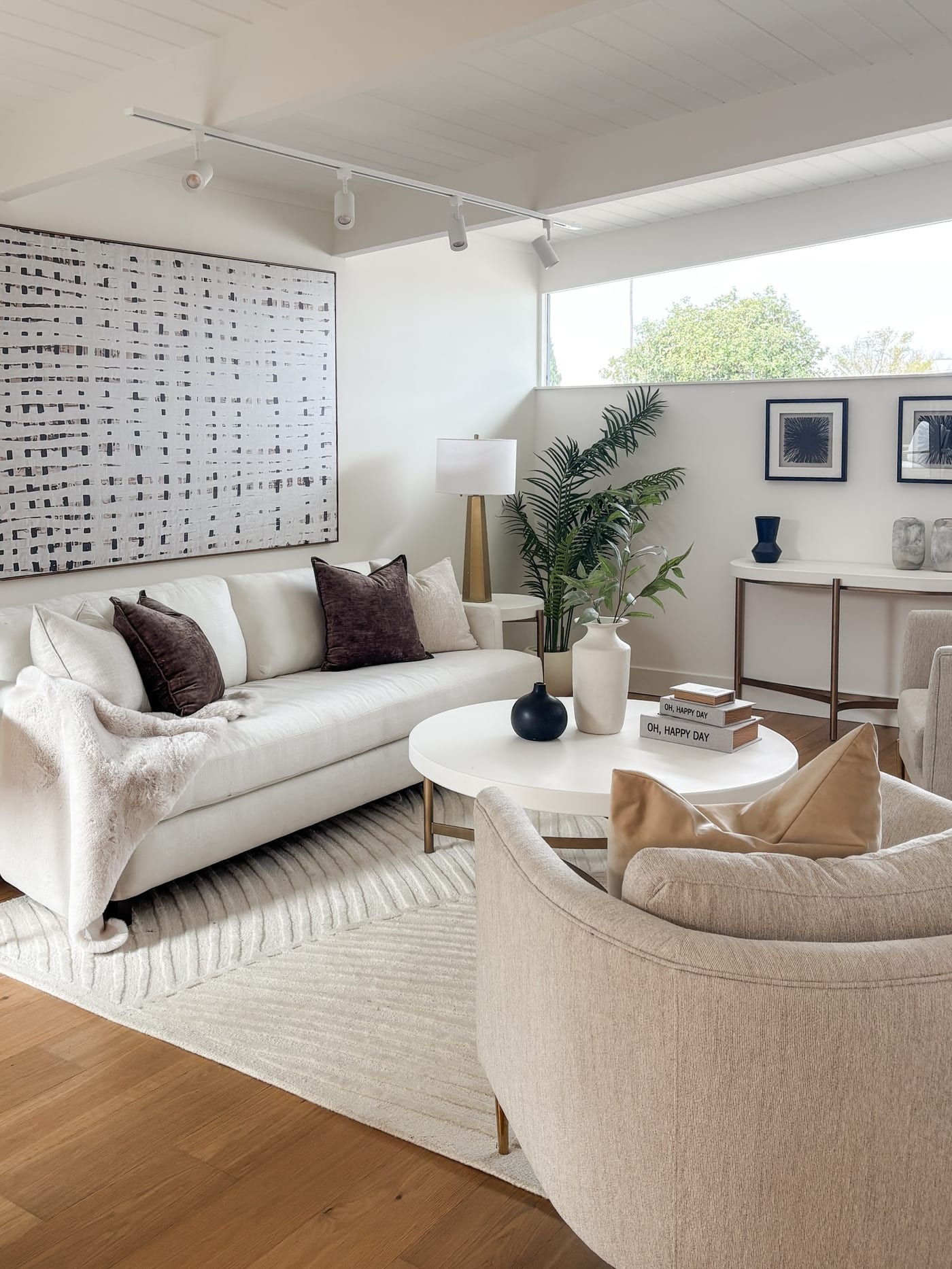 Staged mid-century living room with a white sofa, gridded art, and a round coffee table