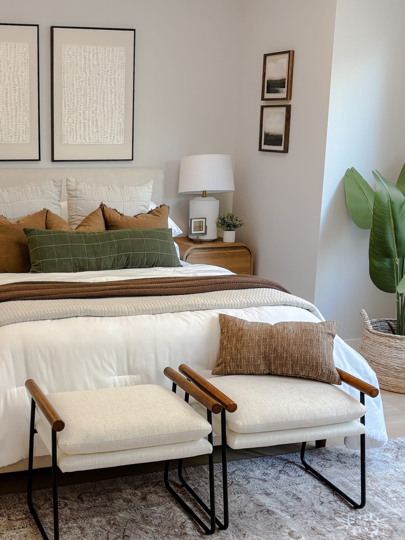 Staged bedroom with olive and rust accents, an upholstered bed, and bench seating