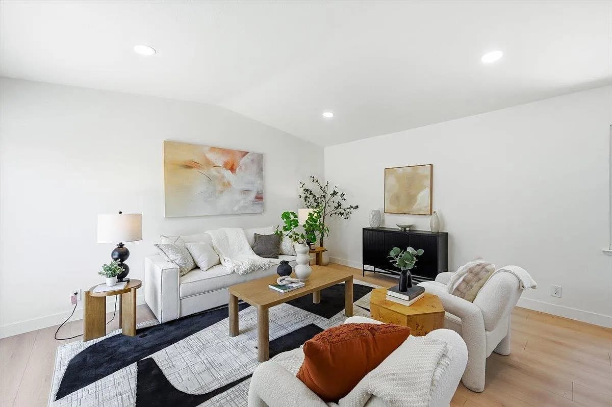 Staged living room with a white sofa, blush abstract art, and a graphic area rug