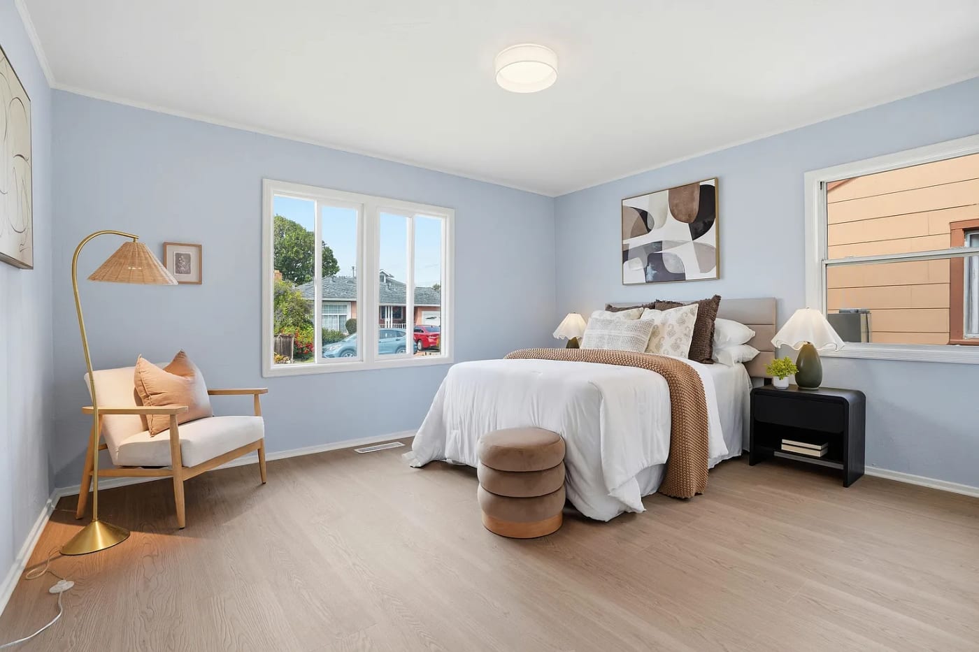 Staged bedroom with soft blue walls, an upholstered bed, and a brass floor lamp