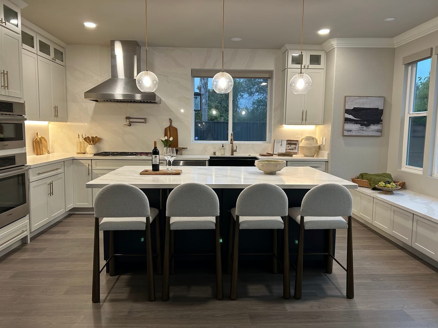 Staged kitchen with a large island, upholstered stools, and glass pendant lights