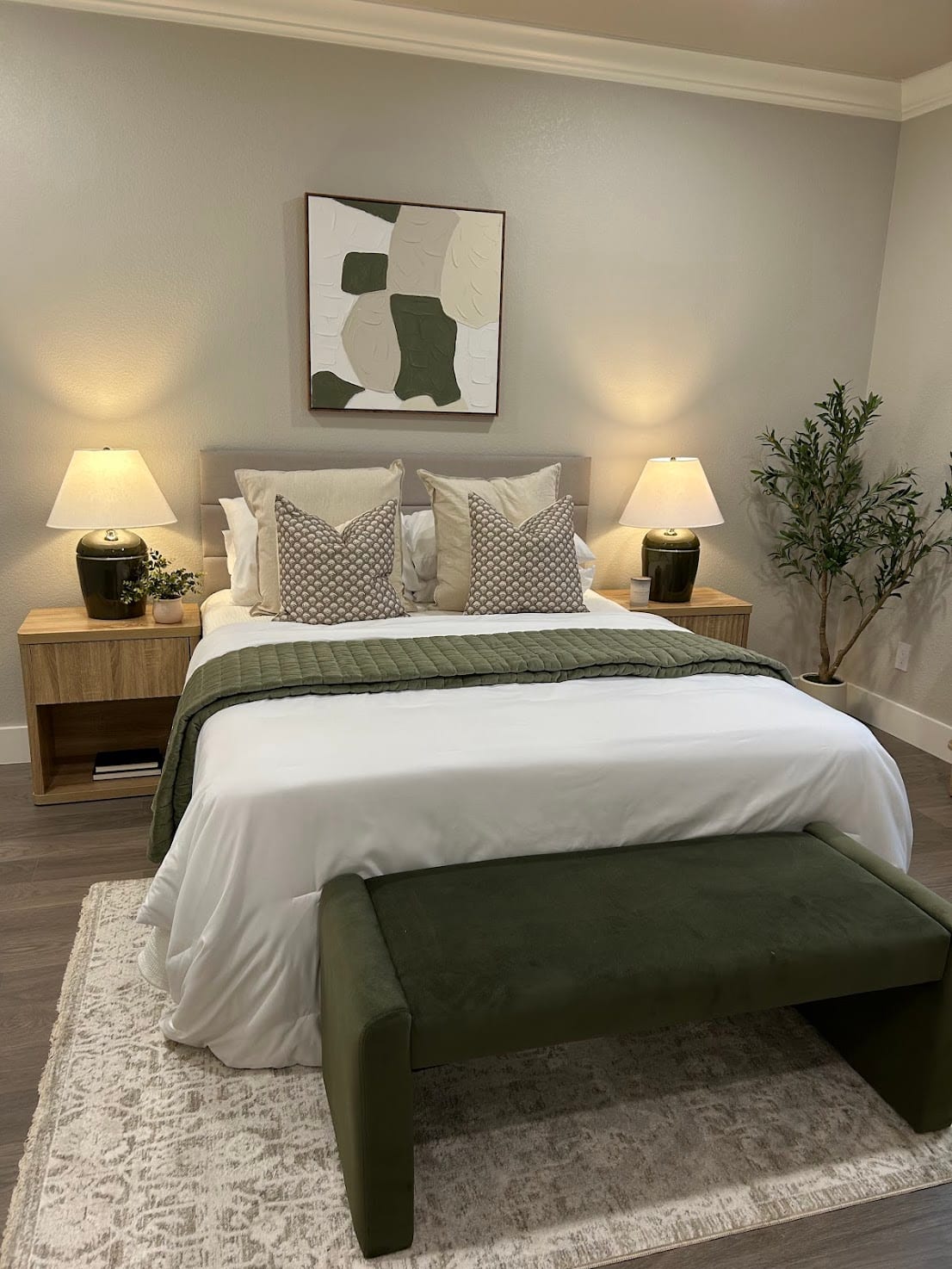 Staged bedroom with an upholstered bed, olive-green accents, and a bench at the foot