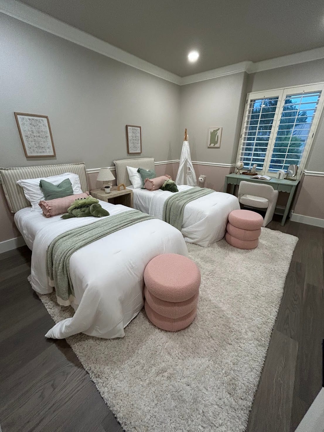 Staged children's room with two twin beds, playful pink and green accents, and a study nook