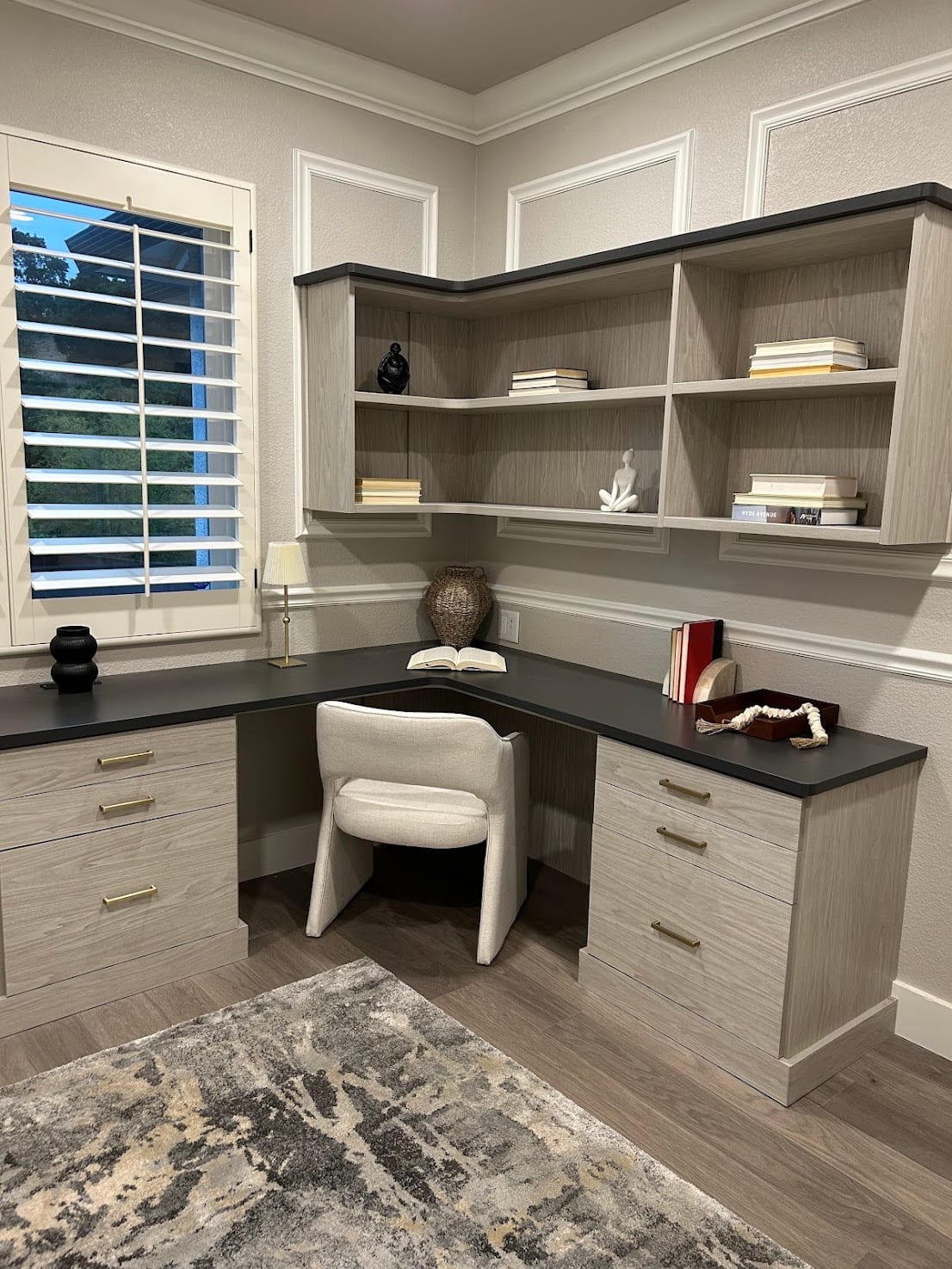 Staged home office with a built-in corner desk, shelving, and an upholstered chair
