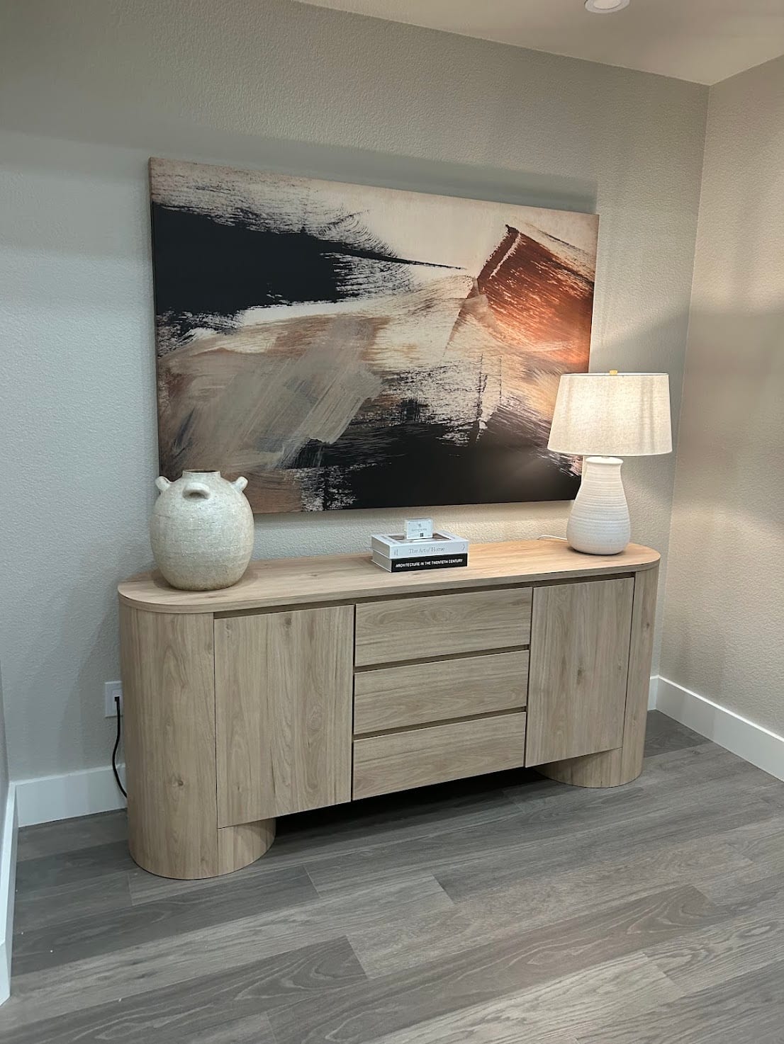 Styled console with a curved oak sideboard and a bold abstract canvas
