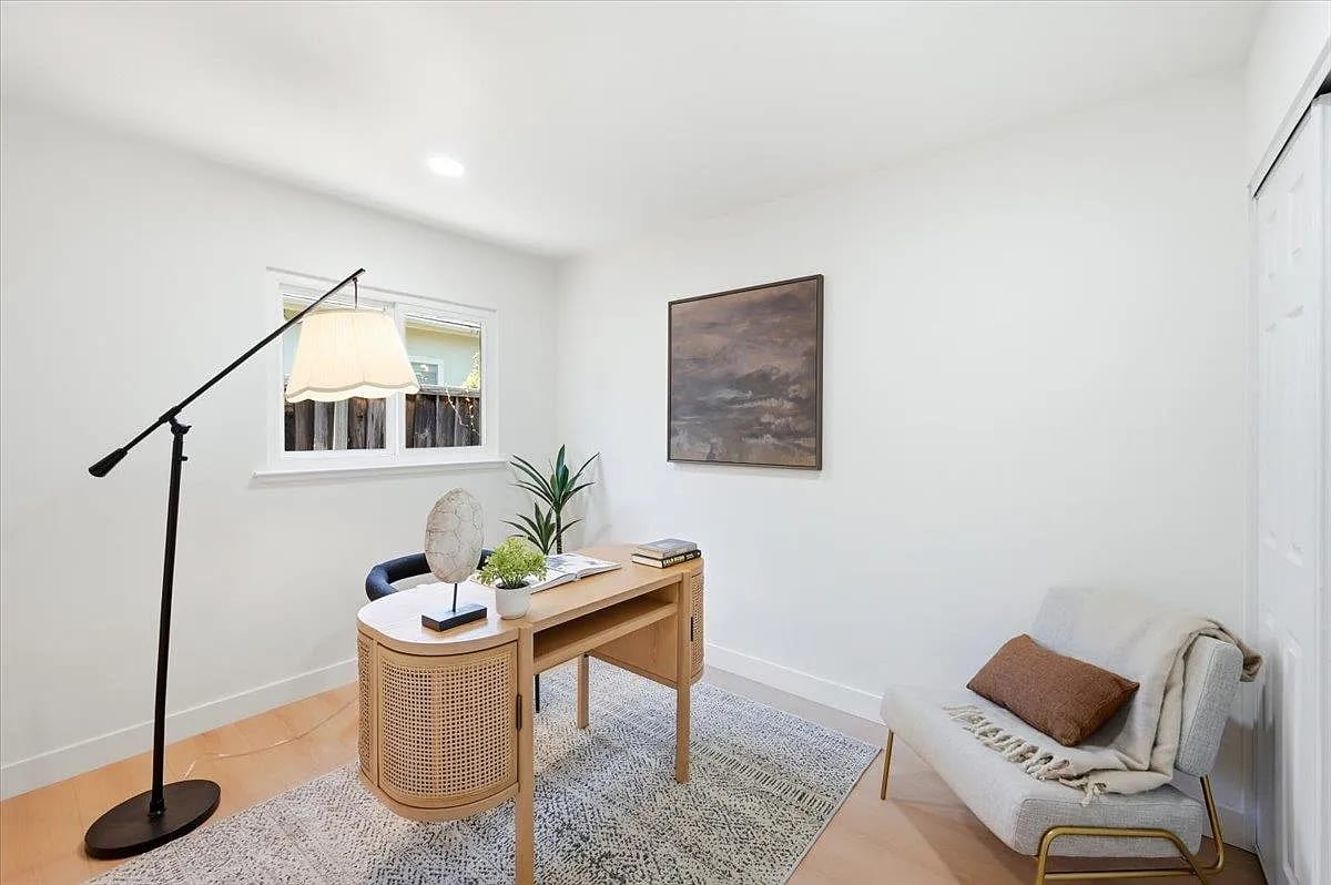 Staged home office with a cane-front desk, accent chair, and moody landscape art