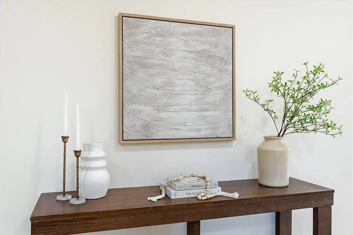 Styled entryway with a dark wood console, textured art, and fresh branches