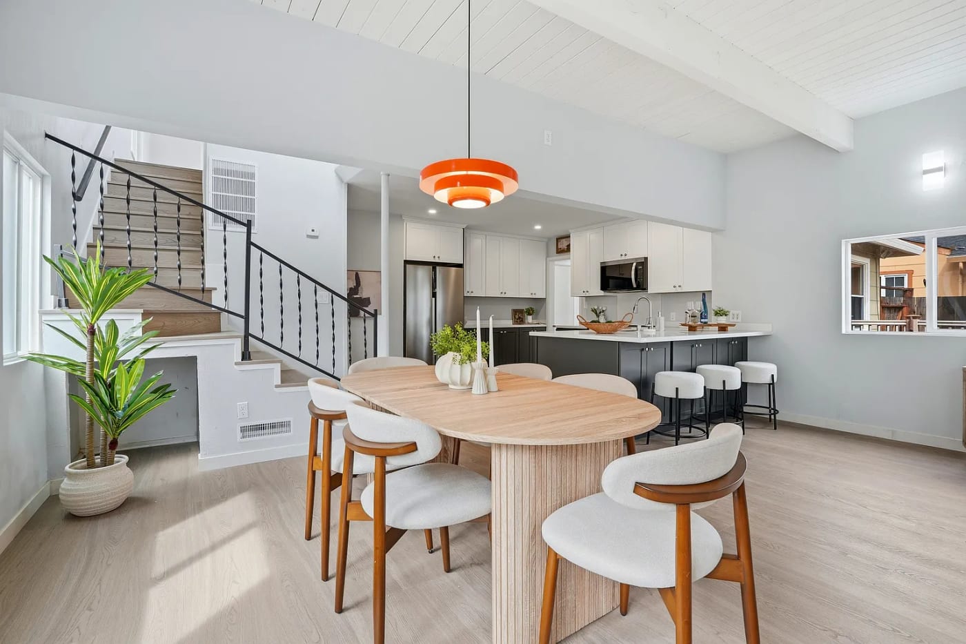 Staged open-plan dining and kitchen with a round pedestal table and pendant light