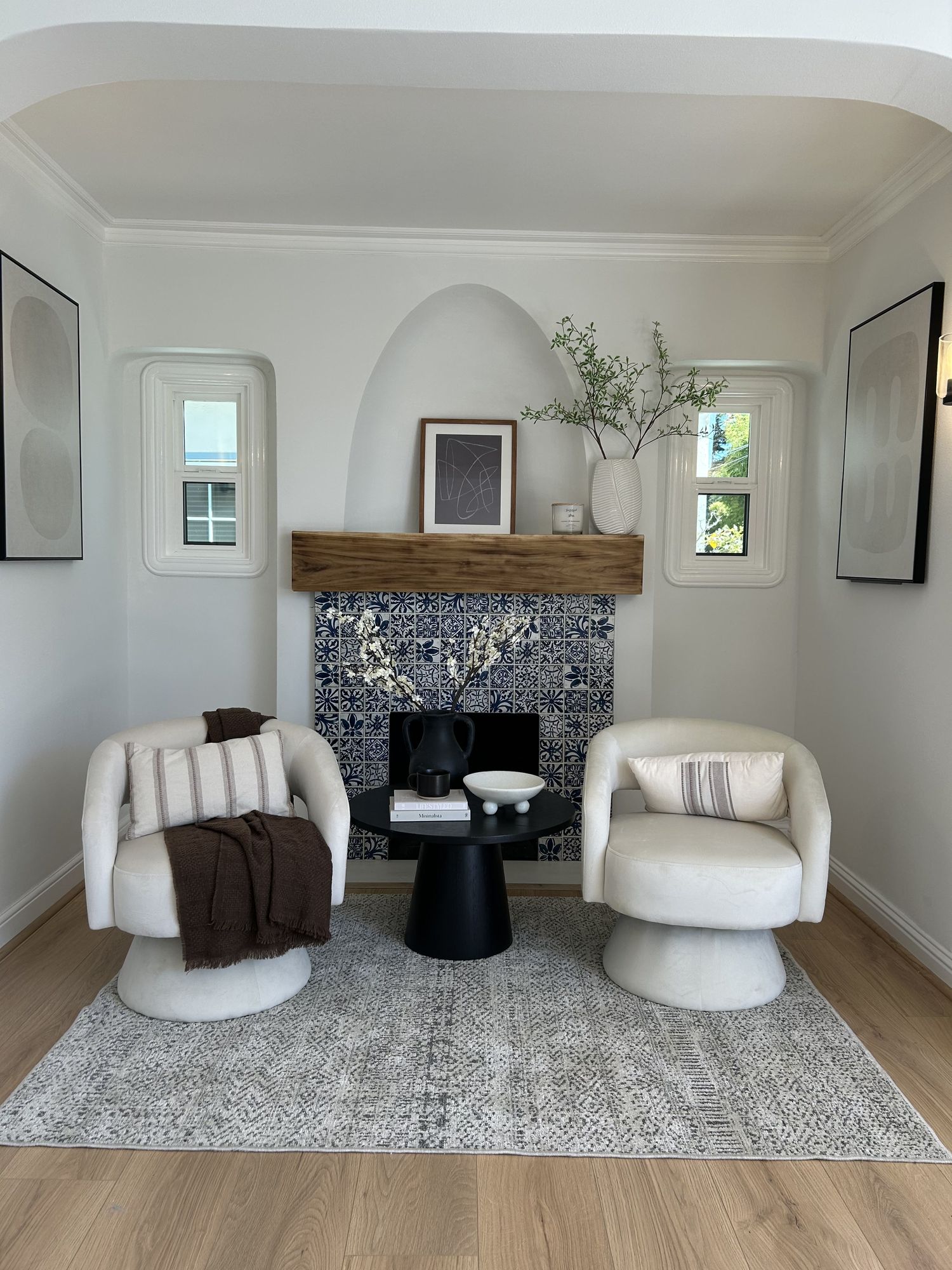 Living room staged by Feather & Pine on Sheffield, Oakland: arched plaster fireplace with a tiled surround and two cream swivel chairs